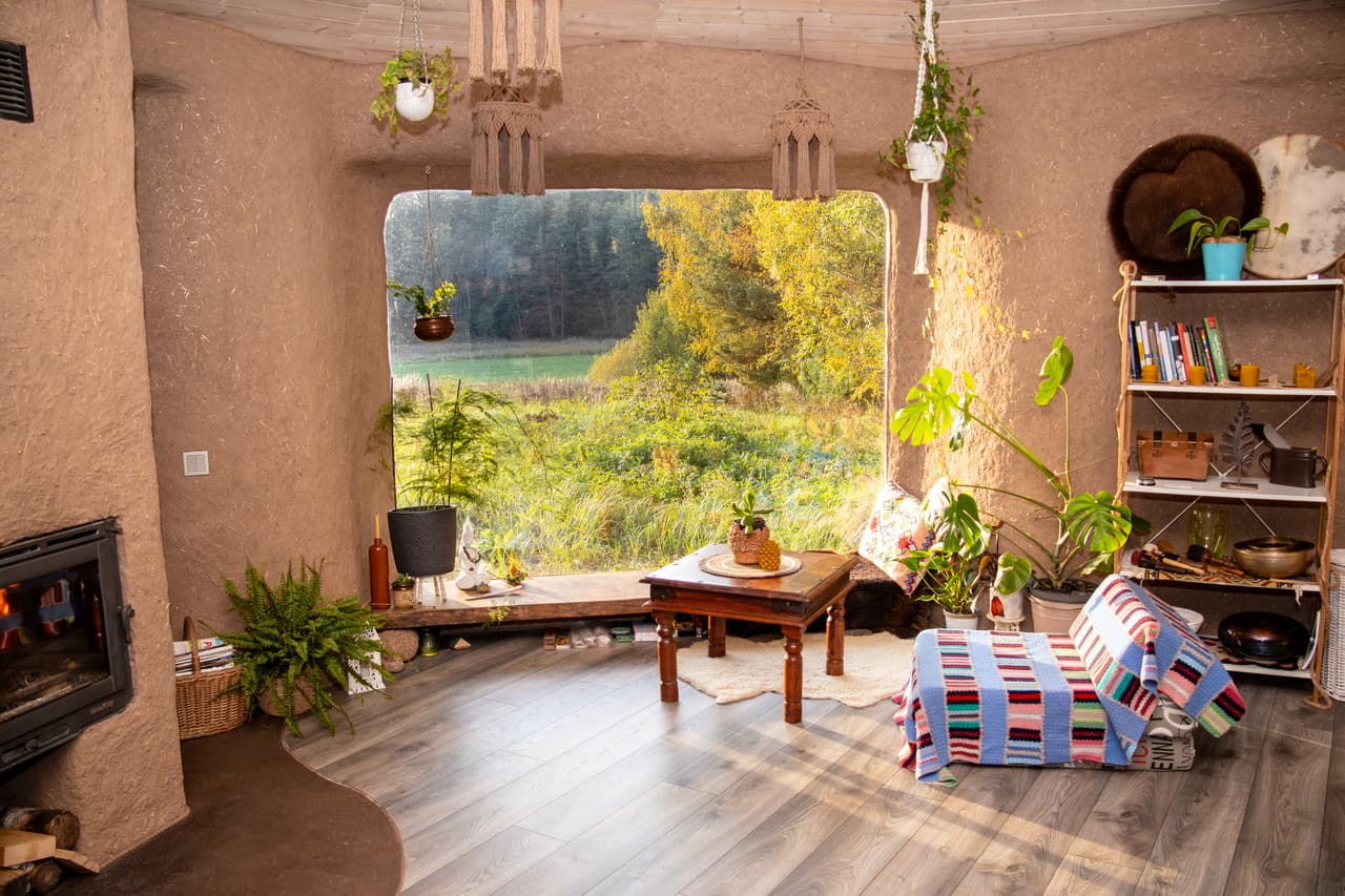 Inside Molinukas: a large window onto the autumn meadow, the fireplace and a bookshelf
